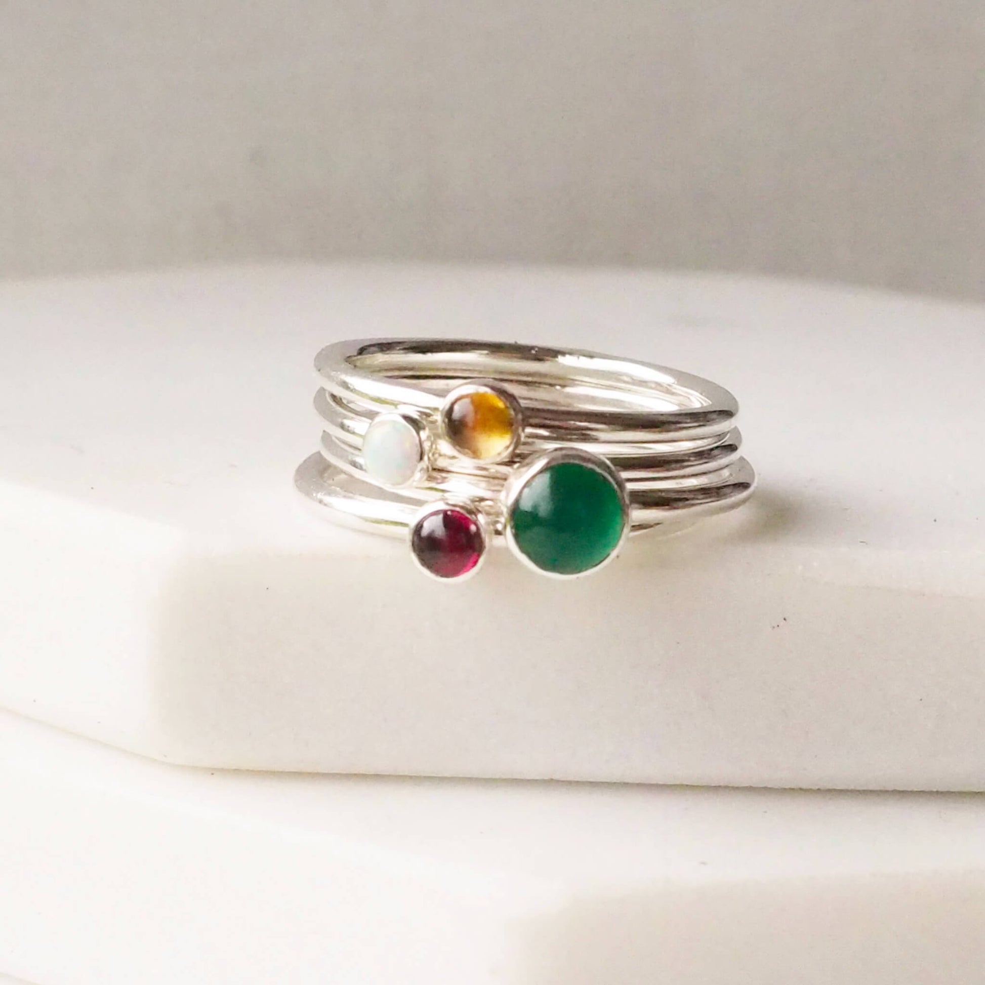 Four rings with the birthstones for May, January, November and October as as a four ring set made by maram jewellery