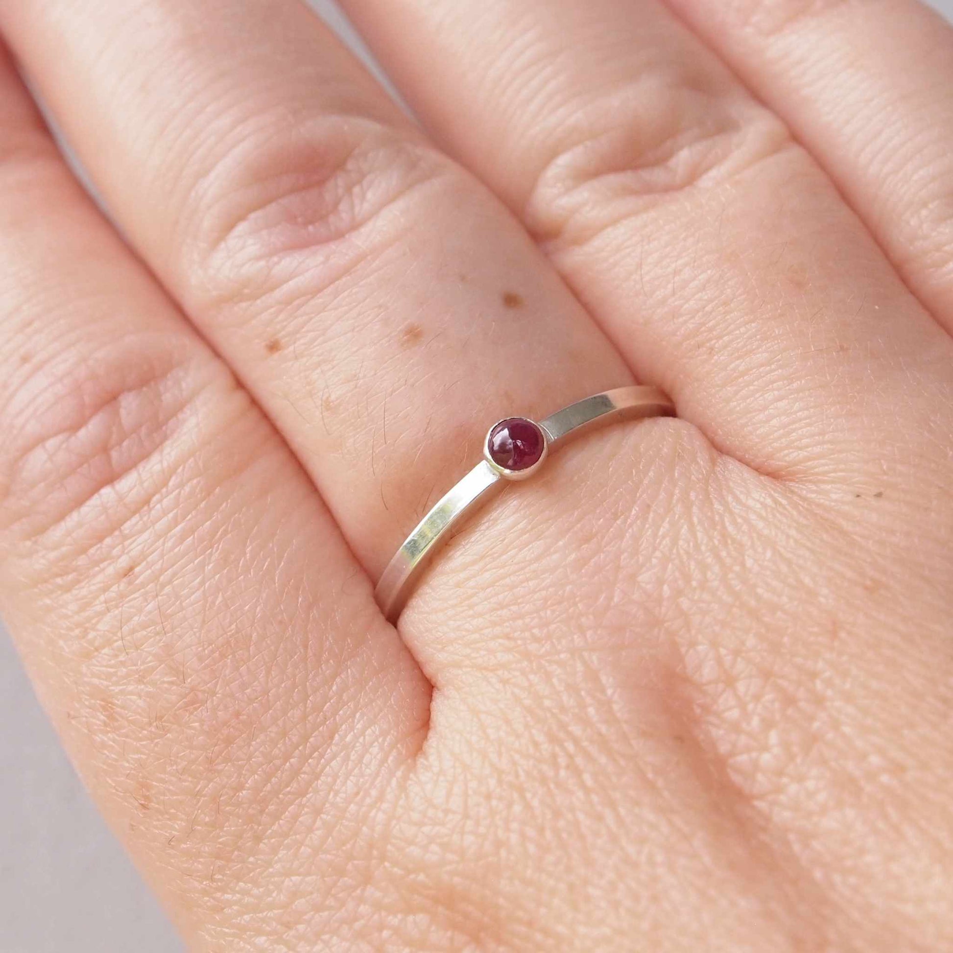 Ruby and Sterling Silver Birthstone Ring for July. The ring is simple in style on a plain square profile band with a small round Ruby in the centre. The ring is handmade to your size by maram jewellery in Scotland