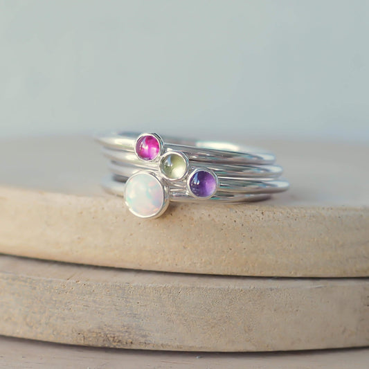 Four ring jewellery set with lab opal, lab ruby, peridot and amethyst to mark various birthstones. Hand made in Scotland by maram jewellery