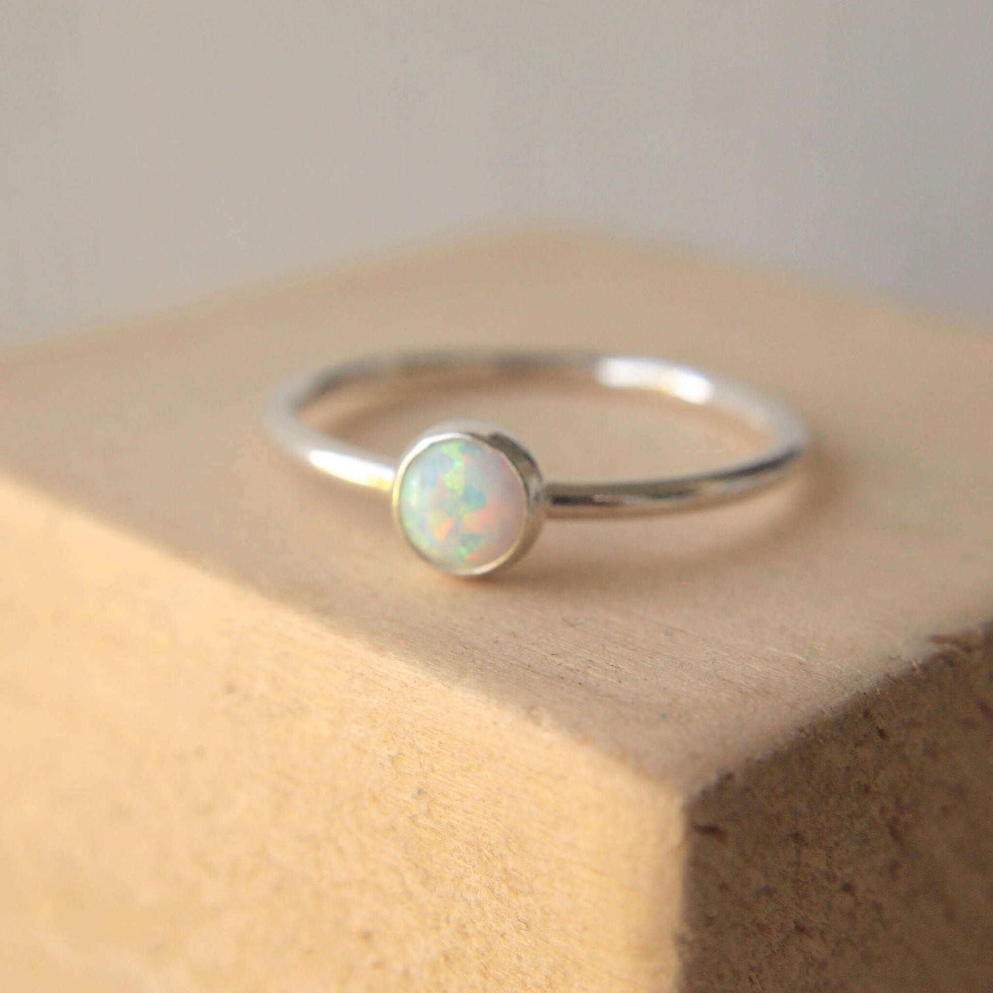 Lab Opal Ring. A 5mm round cabochon in a white synthetic Opal, birthstone for October set very simply onto a round band of sterling silver. Handmade by maram jewellery in Scotland