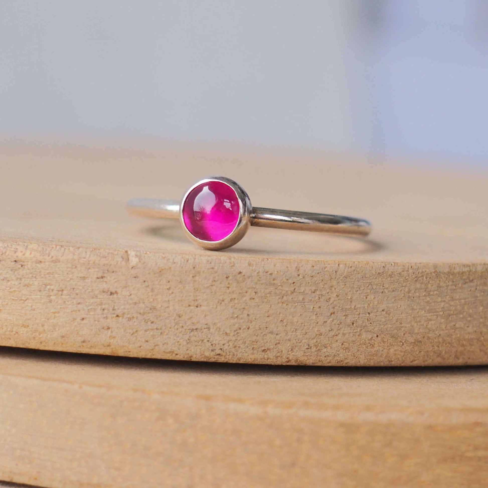 Single Solitaire simple style Sterling SIlver and A Lab Ruby pink Cabochon ring. The lab ruby gemstone is round and measure 5mm and it's set onto a band of fully round wire. It can be made to measure in any size. Handmade in Scotland by Maram Jewellery