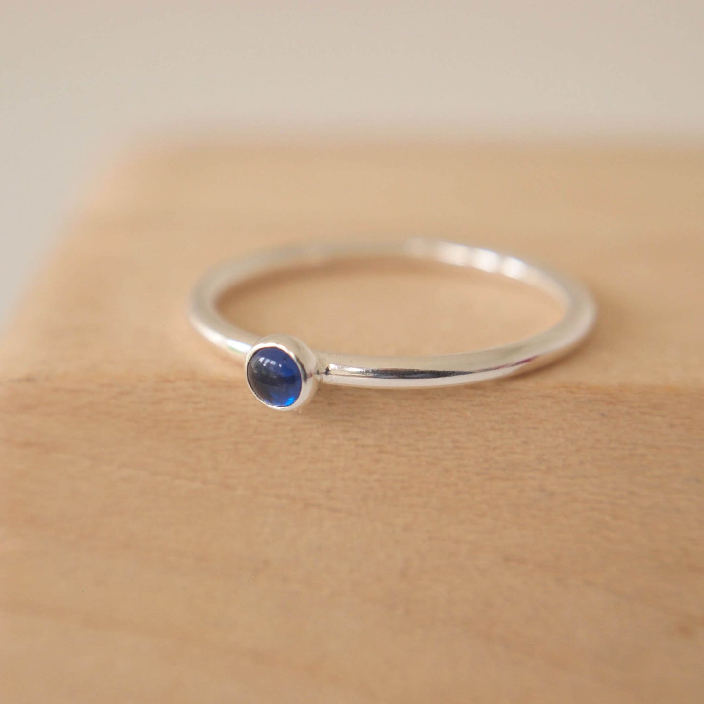 Silver and Lab Sapphire ring on a modern round halo band with a small gemstone. The gem is a 3mm round cabochon in bright primary blue on a simple sterling silver band. Handmade in Scotland by maram jewellery
