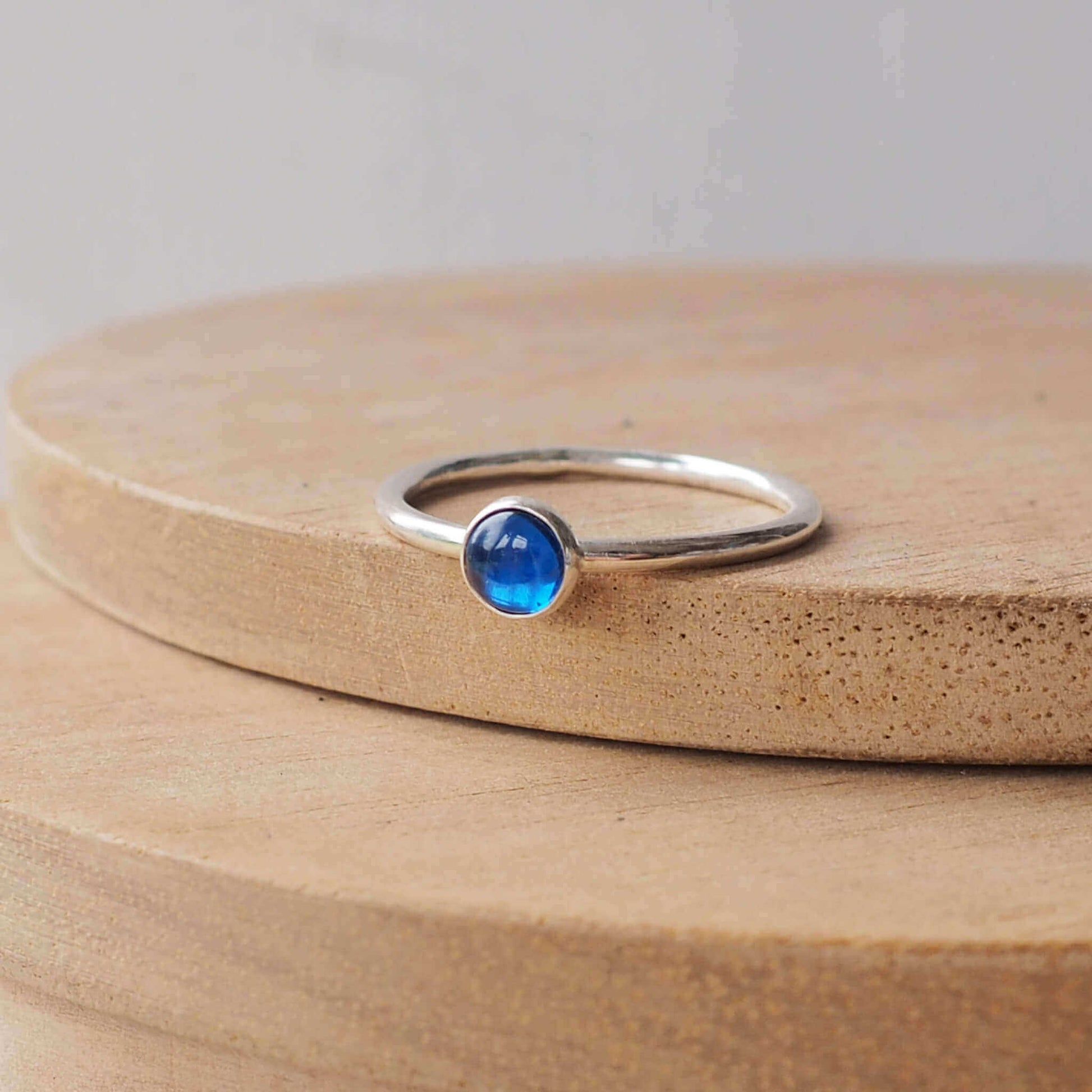 Silver Ring with a round gemstone in a simple style. The gem is a 5mm round lab sapphire cabochon in a bright primary blue. Handmade by maram jewellery in Scotland