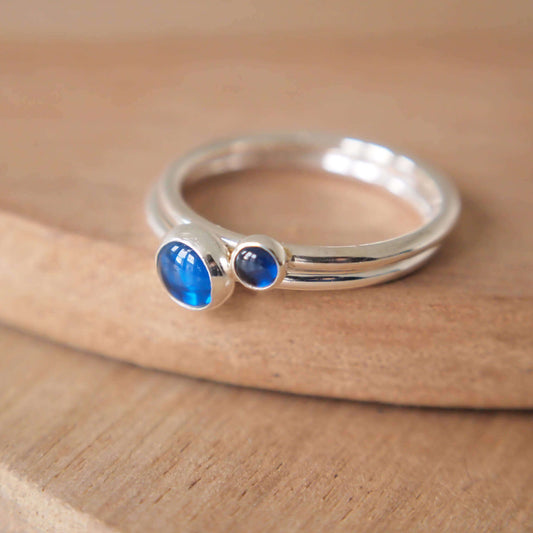 Double Ring set in Sterling Silver and blue gemstones, The rings have two round gemstones of 5mm and 3mm size and are set simply onto round bands of sterling silver. These are September's birthstone and are hand made to your ring size by maram jewellery in Scotland