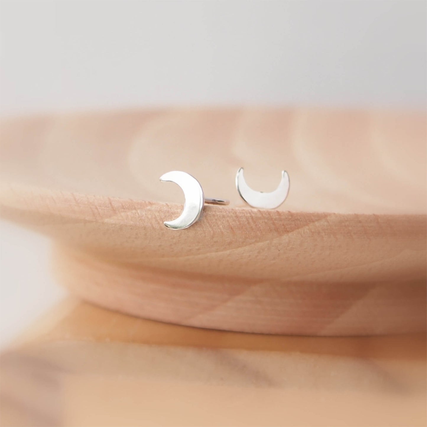 Simple Silver Moon Studs in Sterling Silver measuring a small 11mm in size. Suitable for most ear piercings where a normal stud can be worn and looks great in ears with multiple piercings. Handmade by maram jewellery in Scotland UK