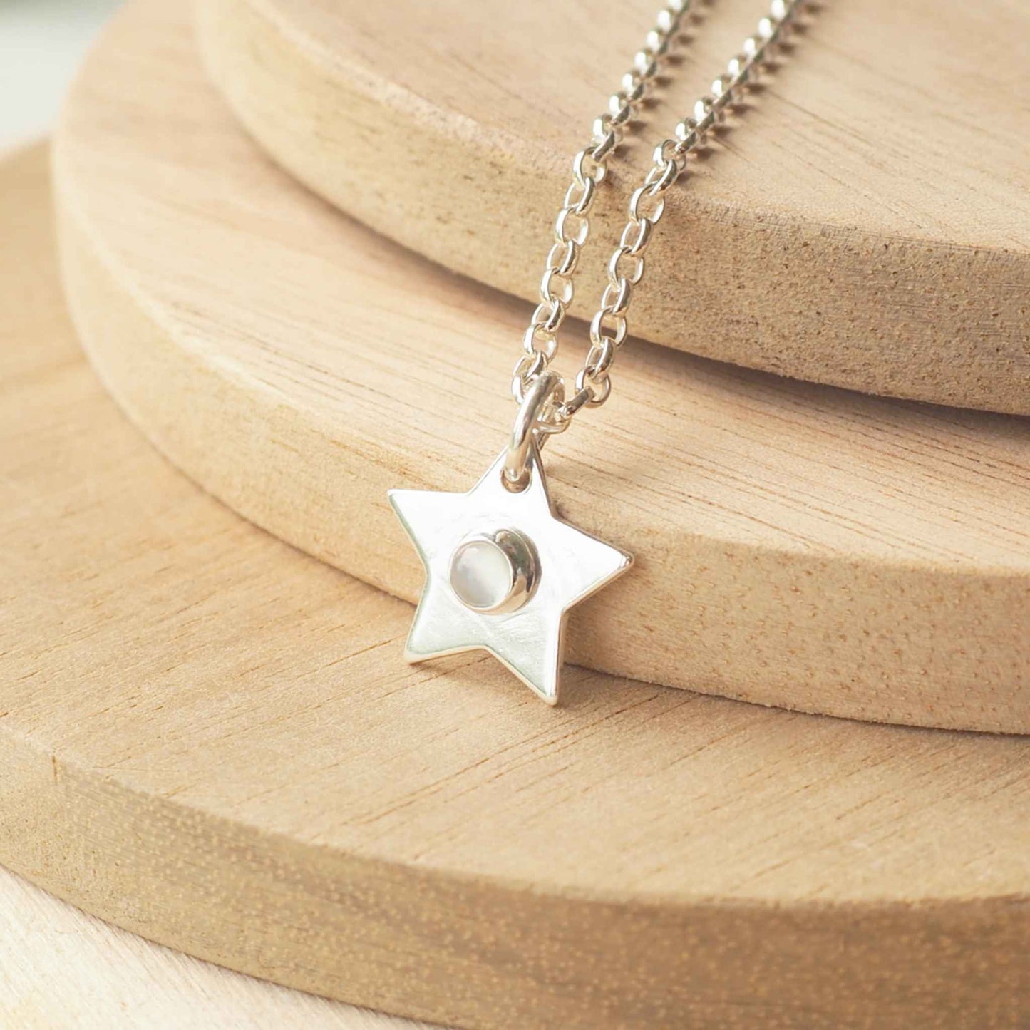 Silver Birthstone star charm pendant with June's birthstone as a centre. Sterling Silver and a round white moonstone gemstone. Handmade by a small jewellery in edinburgh UK