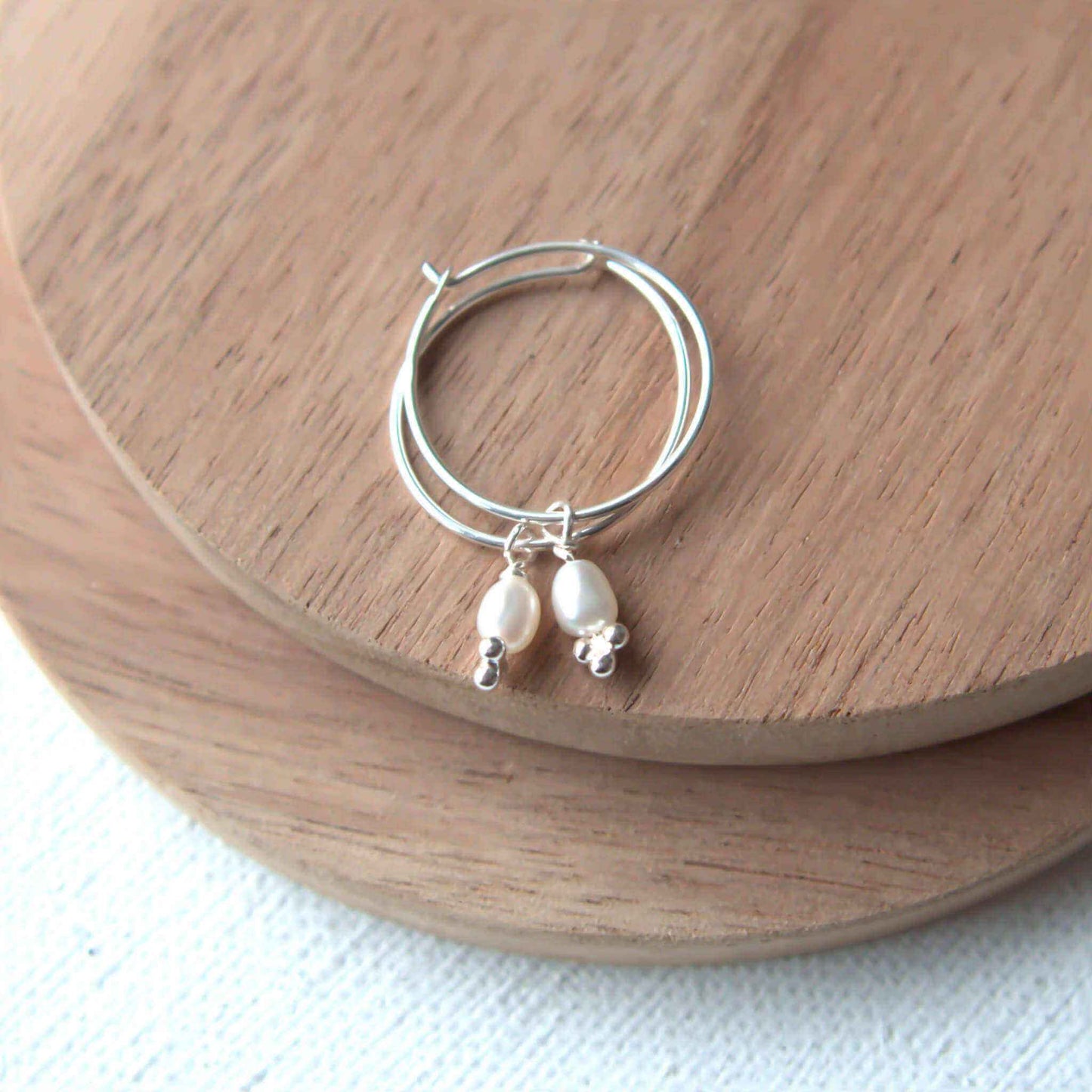 Modern Pearl and Sterling silver hoop earrings with thin silver hoops and a small cream freshwater pearl dangle. Handmade by maram jewellery in Edinburgh.
