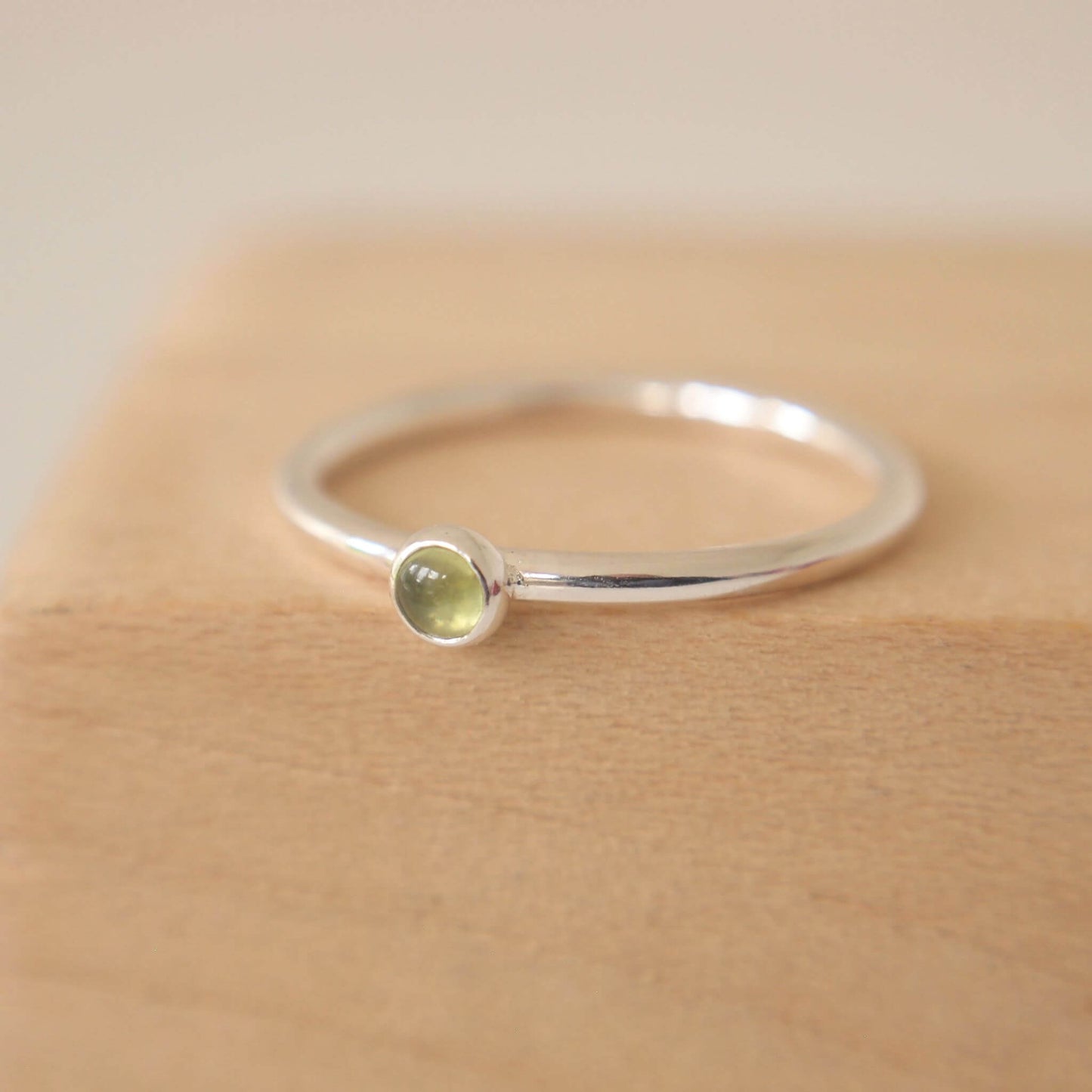 Peridot and Sterling Silver Ring made from a small 3mm round moss green Peridot gemstone set simply onto a modern band of round wire. Handmade to your ring size by maram jewellery in Scotland