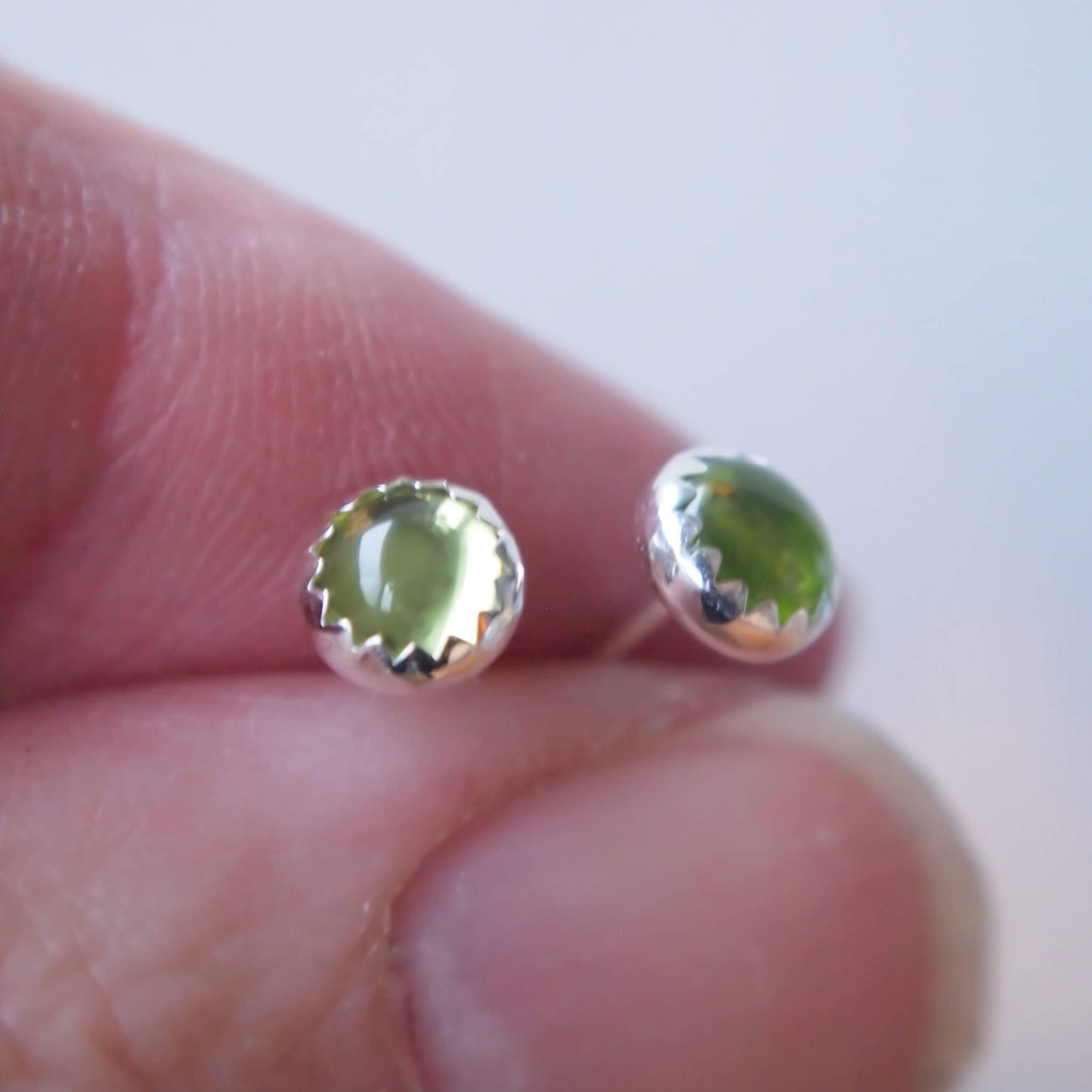 Peridot round gemstone studs with a peridot green cabochon gemstone in a simple silver setting. Handmade by maram jewellery in Scotland UK