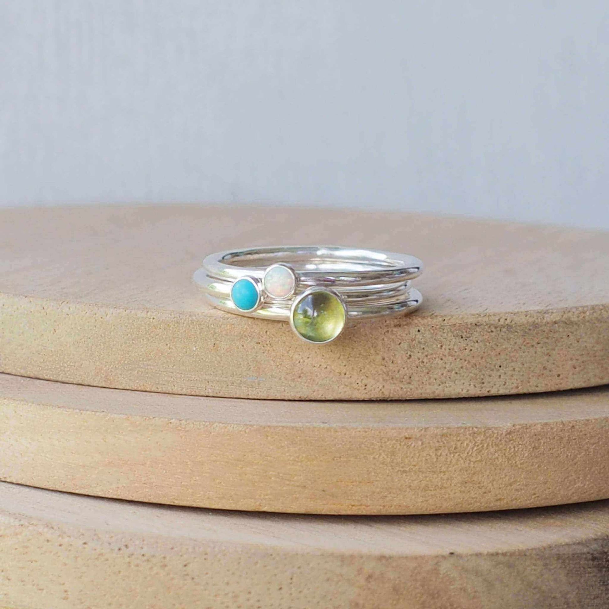 Three ring Ring set made from Sterling Silver, each with a different birthstone in 5mm and 3mm size. This set has a large 5mm round Peridot with a smaller 3mm Lab Opal and Turquoise . Birthstones for August, October and December. Handmade in Scotland by Maram Jewellery.