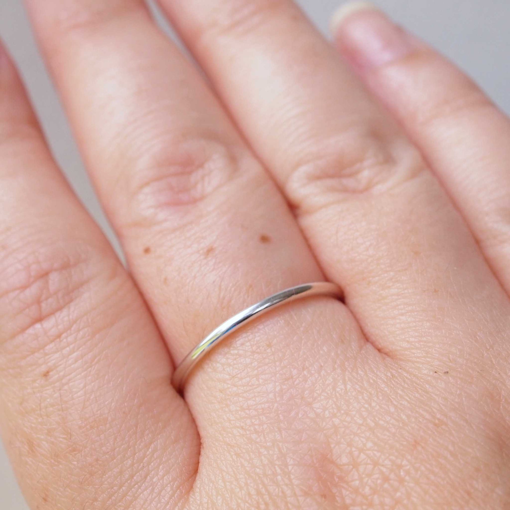 Plain round profile wedding plain band with no details. minimalist sterling Silver ring pictured on a hand. Handmade to your ring size by maram jewellery in Edinburgh UK
