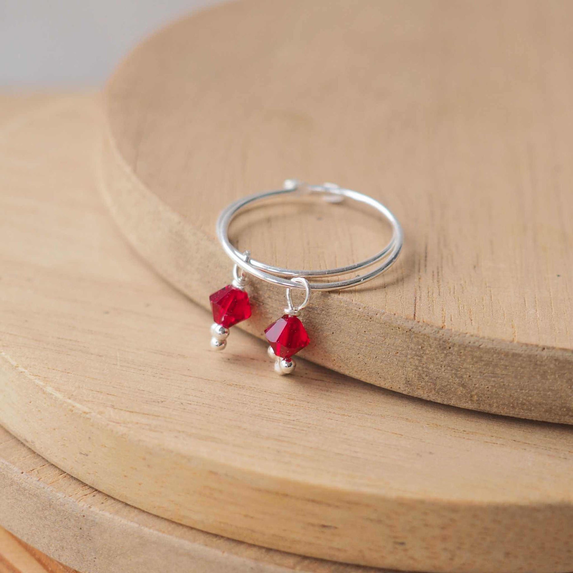 Boho style simple wire hoop earrings with a red crystal dropper. Simple birthstone hoop earrings with a red January birthstone crystal. handmade by an indie jeweller in Edinburgh UK