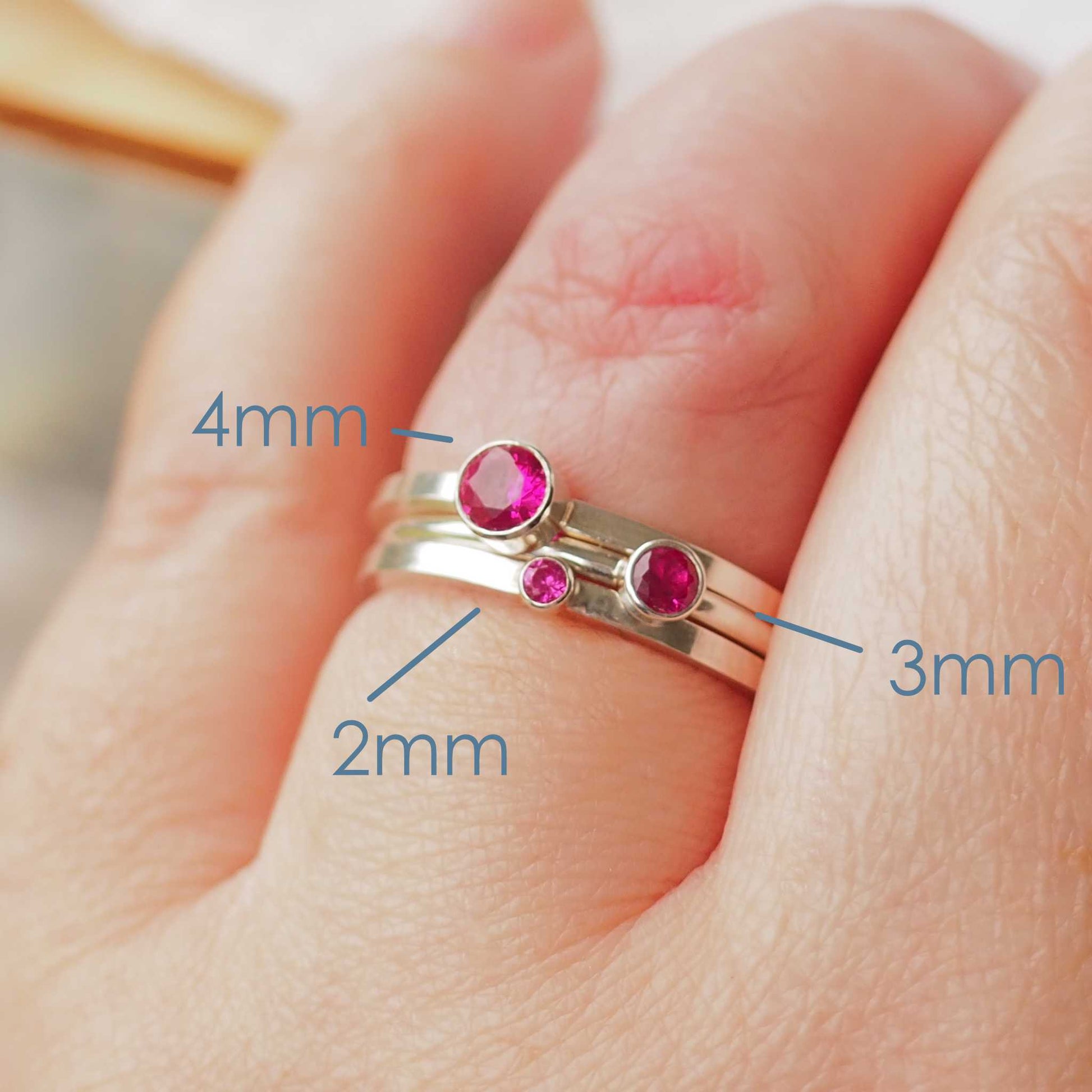 Three rings showing the square and round band styles with three different sized Cubic Zirconia in a Hot pink colour. The rings are made from Sterling Silver and a round rich pinky red  cubic zirconia measuring 2,3 or 4mm in size. Handmade by maram jewellery in Scotland