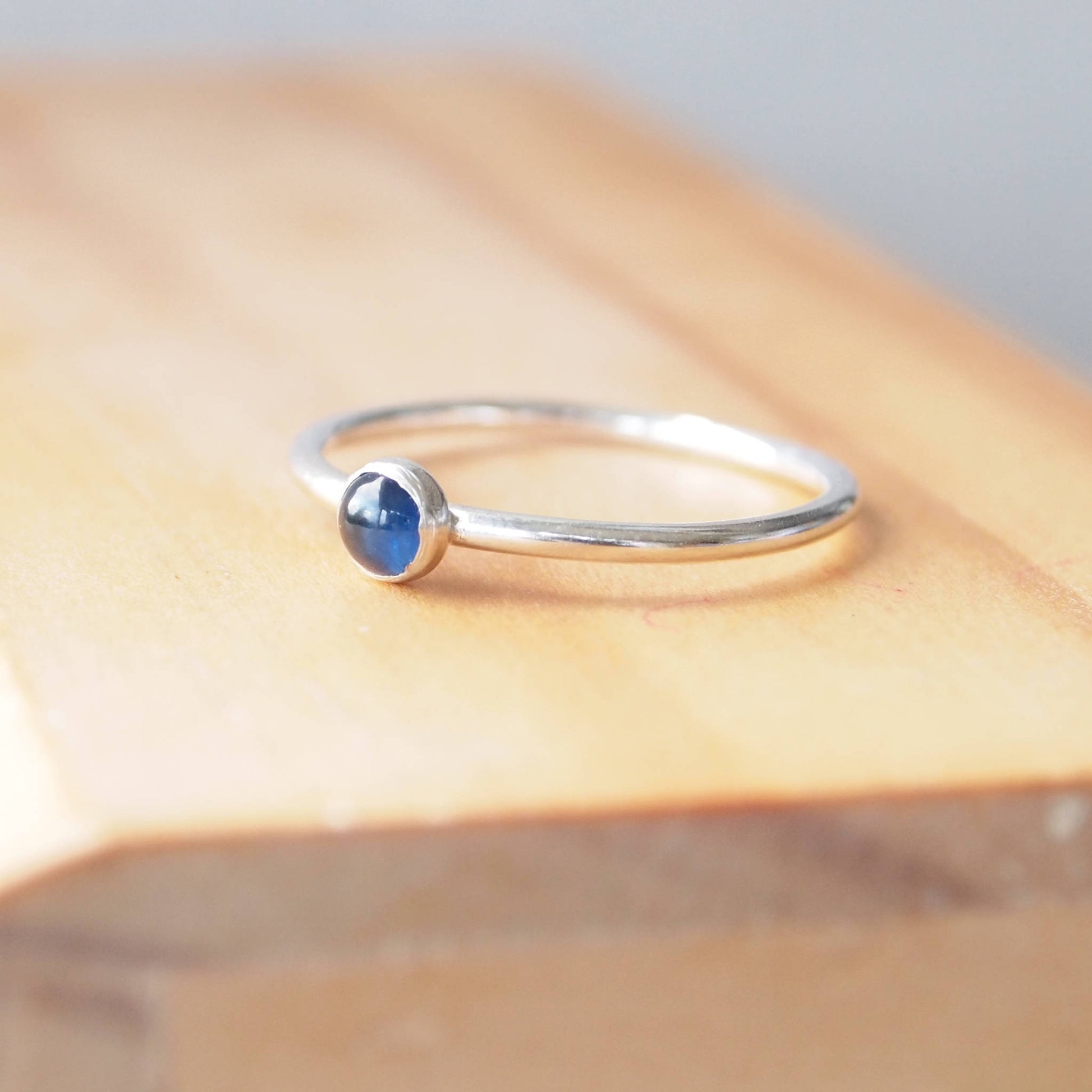 Simple Solitaire ring with a genuine Sapphire gemstone. The ring is made from Sterling Silver and a round natural sapphire measuring 4mm in size. It is set onto a modern ring with a fully round profile. The ring is handmade to your ring size  by maram jewellery in Scotland UK