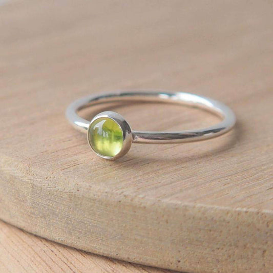 Single solitaire sterling silver ring with a round 5mm green Peridot. The ring is made in a minimalist simple style with a 5mm round cabochon set onto a modern halo fully round band. Made to order to your ring size, and handmade in scotland by maram jewellery
