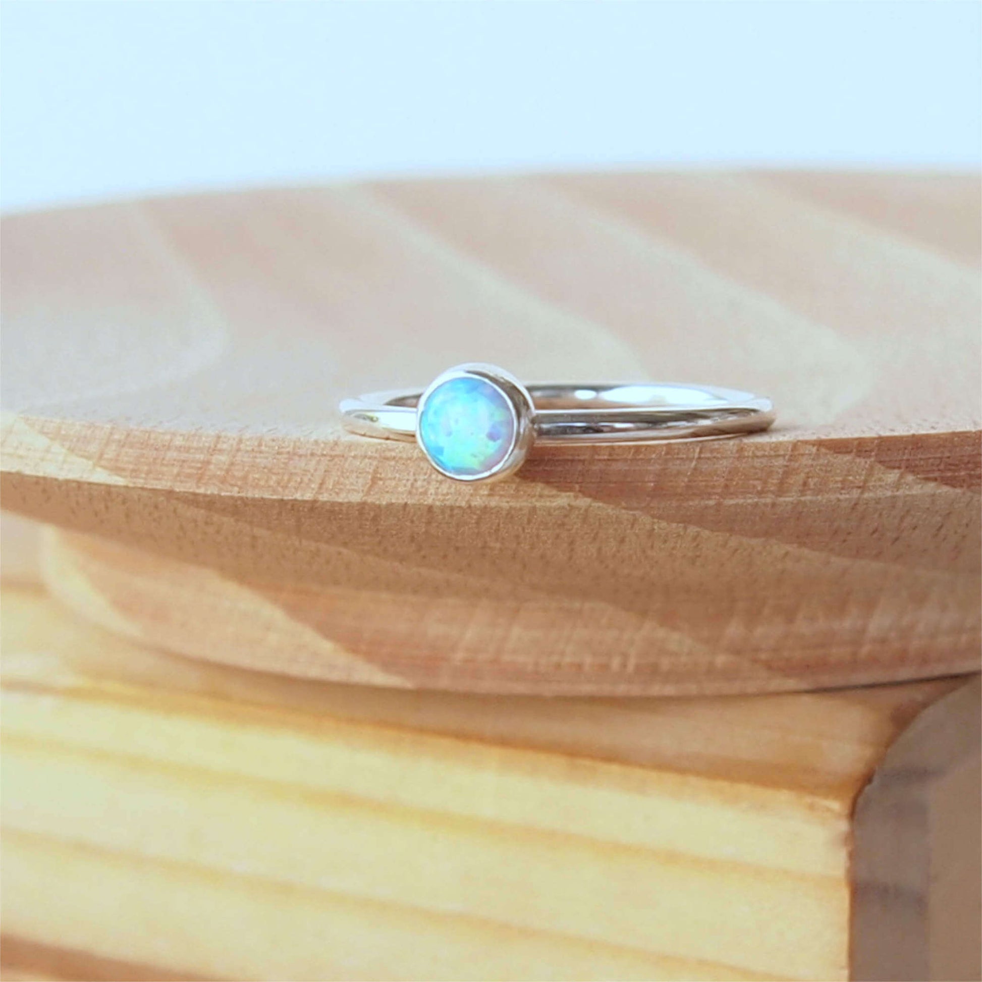 Simple style Lab Opal and Sterling Silver single Solitaire Ring with Lab Opal. Opal is Birthstone for October. THe round 5mm gem is a blue opal with lots of iridescence. Handmade by Maram Jewellery in Scotland