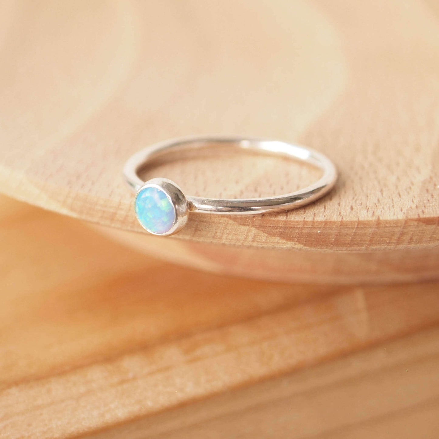 Simple style Lab Opal and Sterling Silver single Solitaire Ring with Lab Opal. Opal is Birthstone for October. THe round 5mm gem is a blue opal with lots of iridescence. Handmade by Maram Jewellery in Scotland