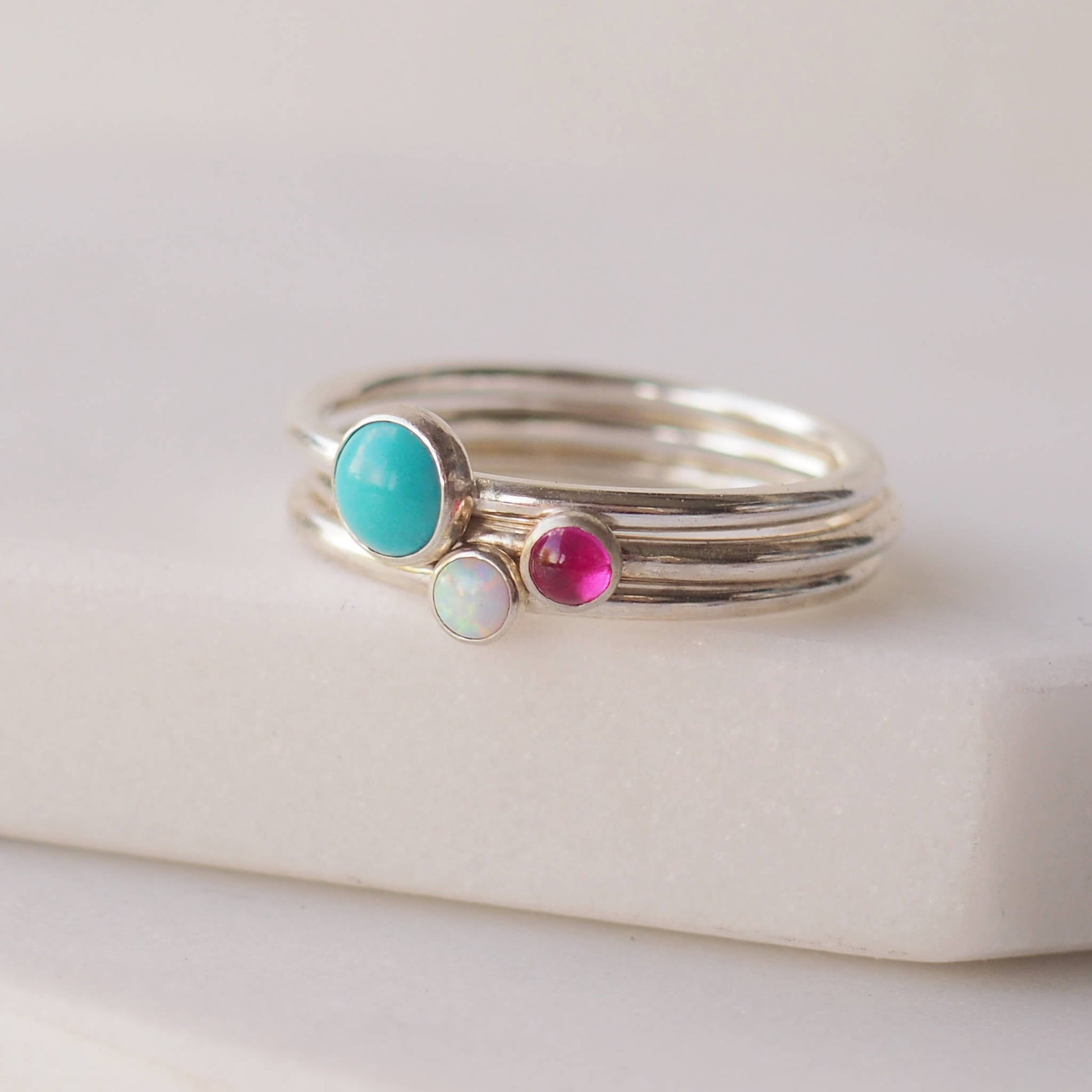 Three ring birthstone set with a large Turquoise, smaller  Lab Opal and Lab Ruby. Handmade by maram jewellery in Scotland UK 