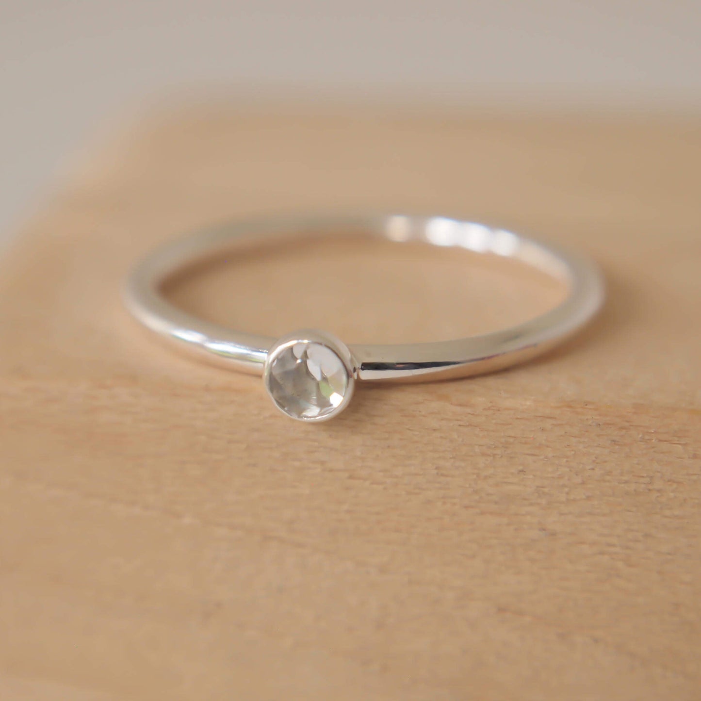 White Topaz and Sterling Silver Birthstone RIng for April. The ring is simple in style on a plain fully round band with a small round facet cut pale white topaz in the centre. The ring is handmade to your size by maram jewellery in Scotland