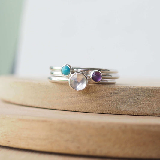 Three Silver Ring Birthstone set with April, February and December Birthstones. The set has three round cabochon stones, a 5mm round faceted clear white topaz, a 3mm purple amethyst and a 3mm aqua Turquoise. Handmade in Scotland by Maram Jewellery
